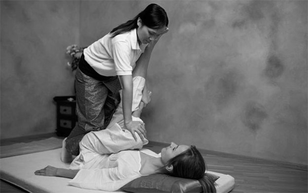 Mulher fazendo massagem tailandesa em cliente