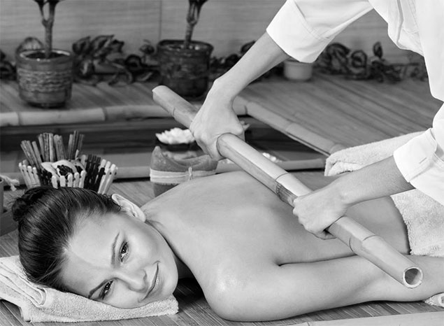 Mulher recebendo massagem de bambuterapia